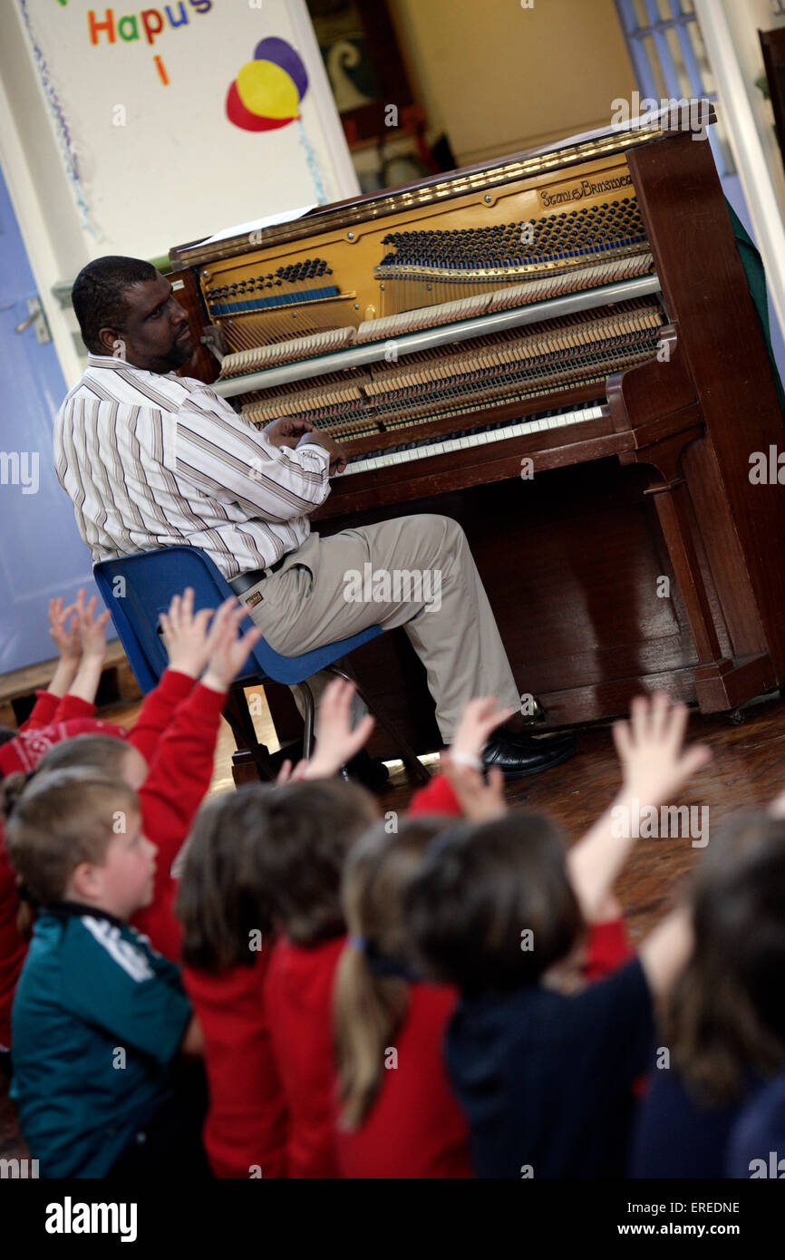 Music workshop with a painist playing in front of a class of children Stock Photo