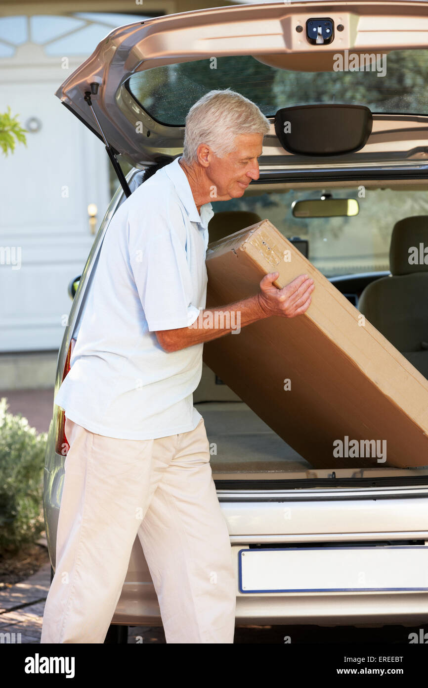Senior Man Loading Large Package Into Back Of Car Stock Photo