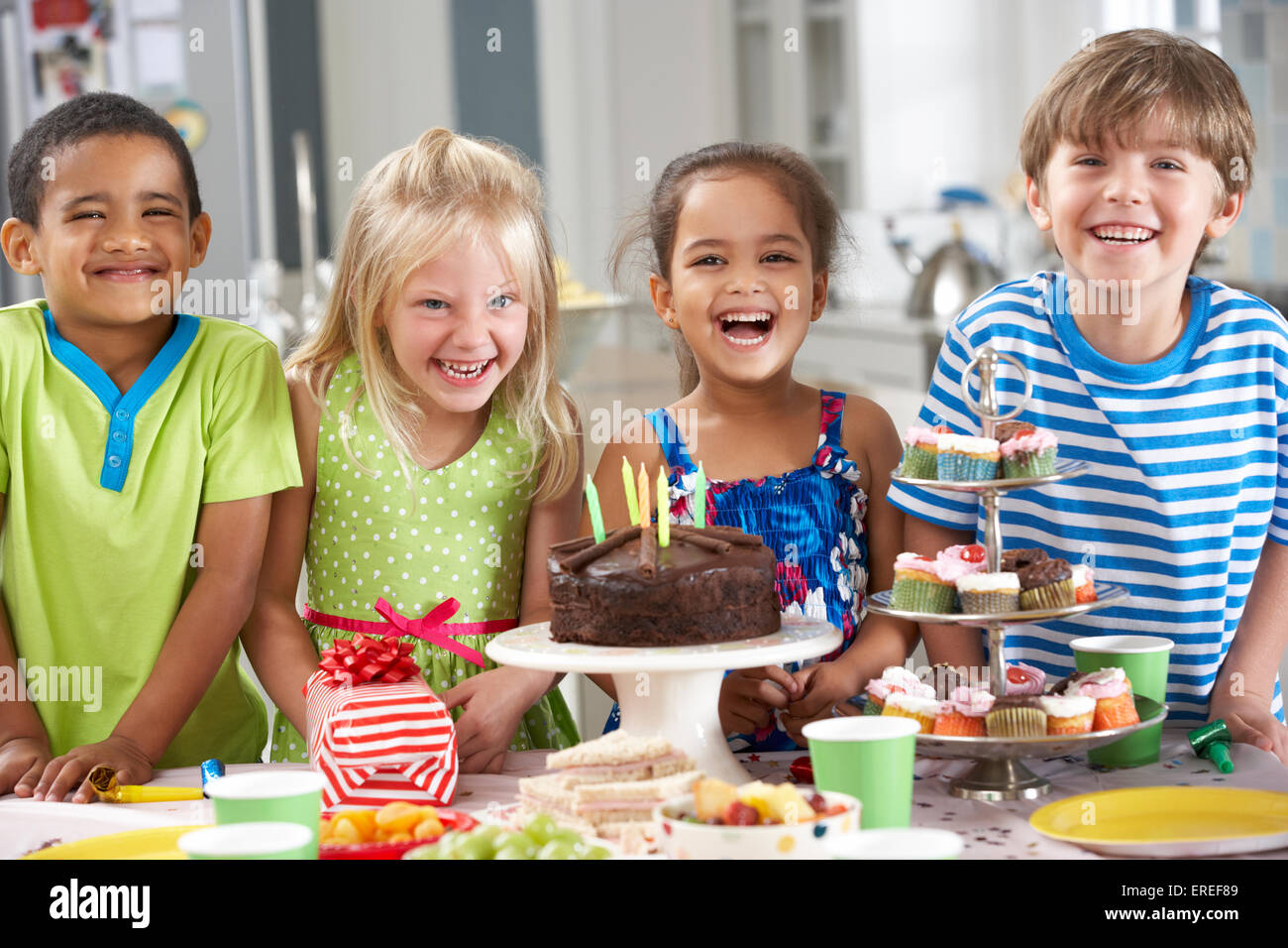 Group Of Children Standing By Table Laid With Birthday Party Food Stock
