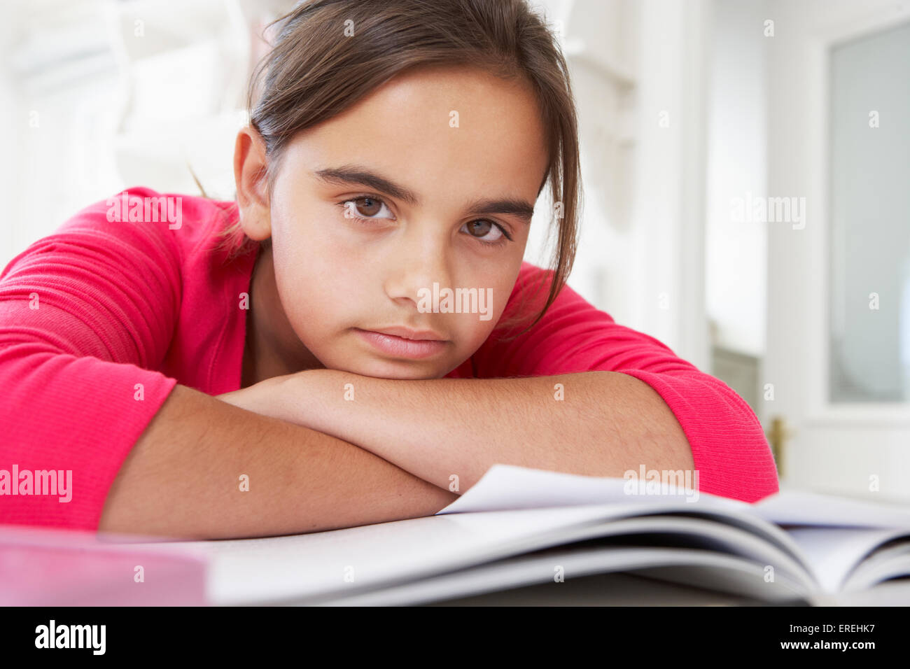 Bored Young Girl Doing Homework At Desk In Bedroom Stock Photo