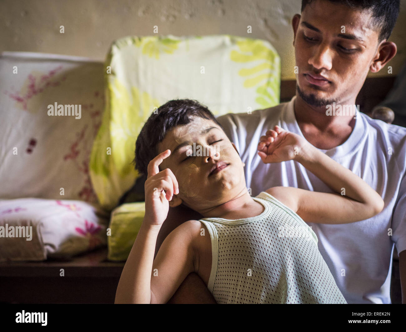 Kulai, Johore, Malaysia. 2nd June, 2015. A Rohingya man takes care of MOHAMMAD SHIDE, 6 year old, Rohingya refugee. The man helps take care of the boy when his mother is at work. The child was born healthy but developed symptoms similar to polio before they came to Malaysia from Myanmar. Now his mother can't afford a proper medical diagnosis and his condition is worsening. He is now blind and losing control of his muscular system. His mother doesn't know what is wrong with him Credit:  ZUMA Press, Inc./Alamy Live News Stock Photo