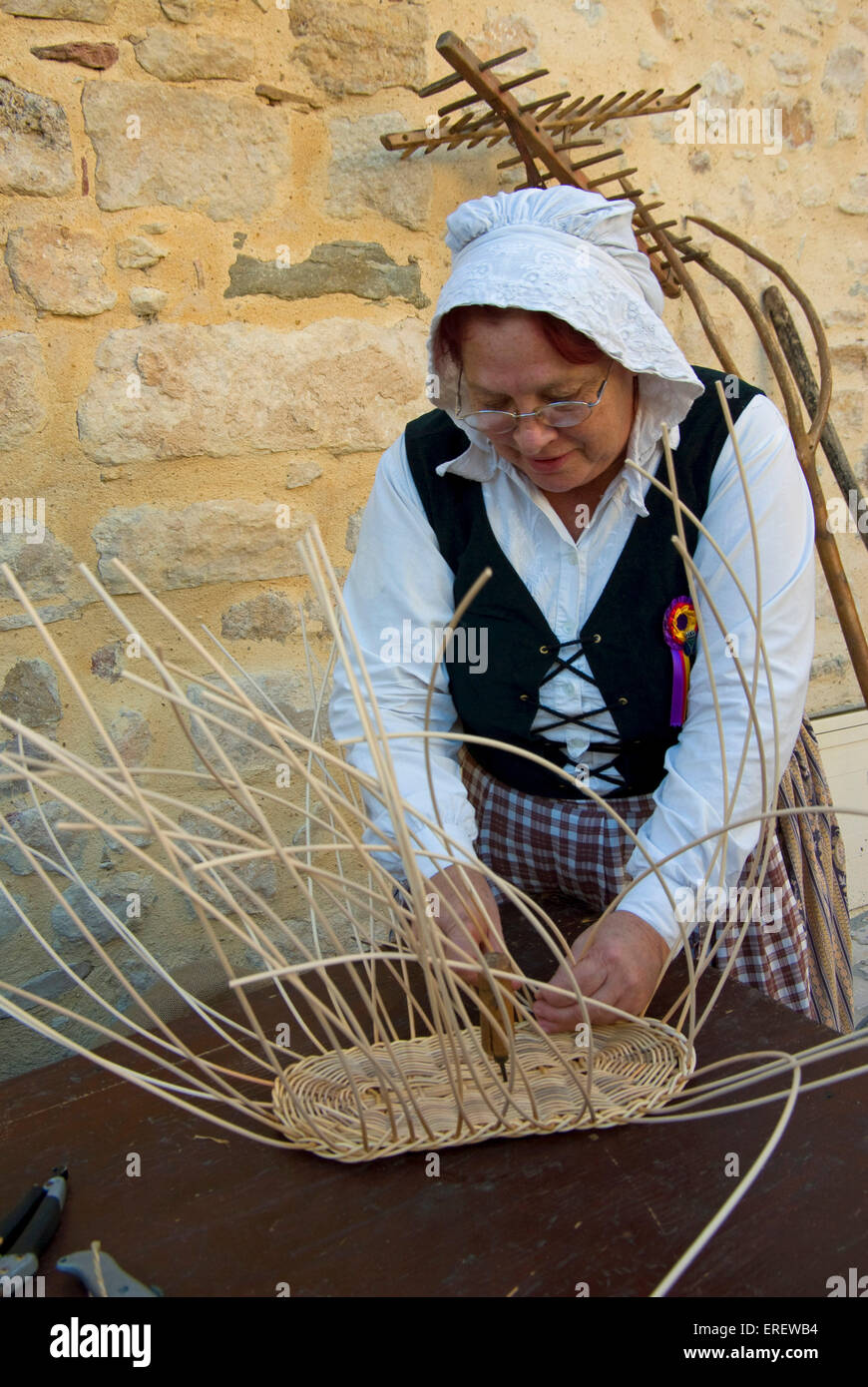 Female basket weaver in oldfashioned dress demonstrating this