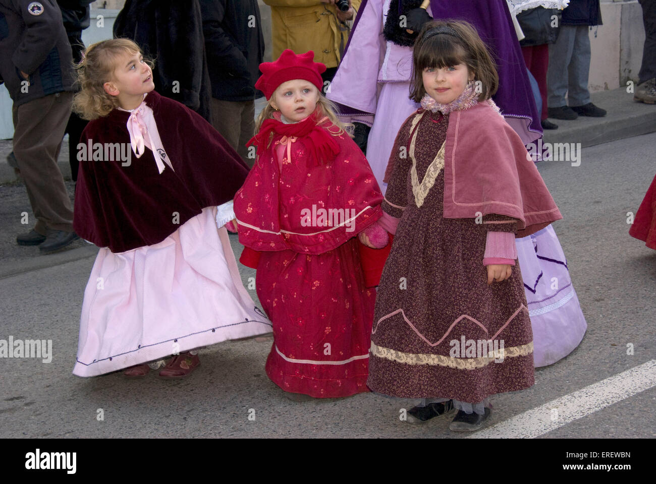 Three small girls in Victorian costumes taking part in a Valentine's Day parade in Roquemaure, South of France. Stock Photo