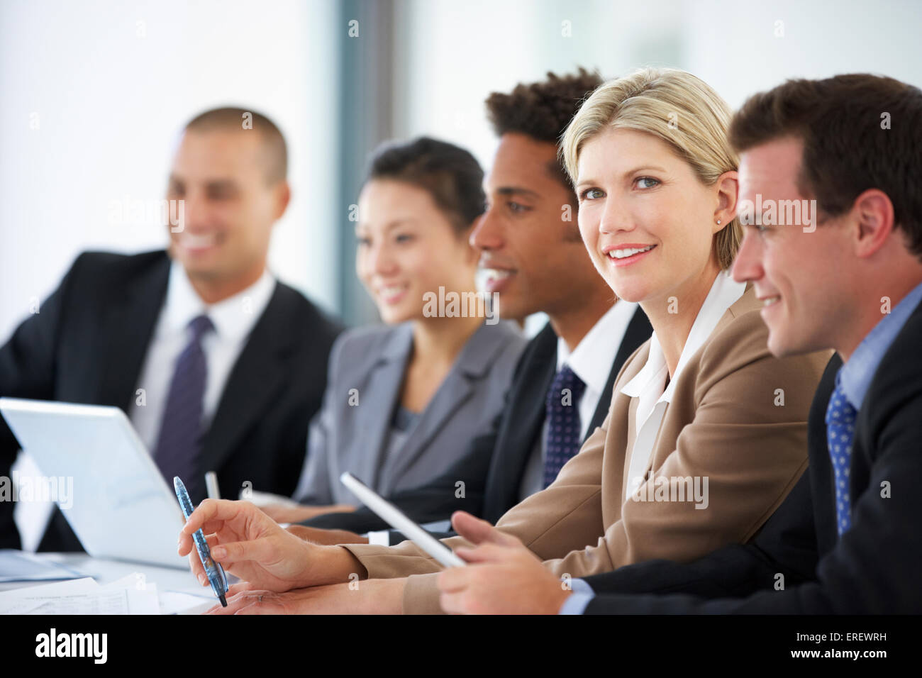 Portrait Of Female Executive Attending Office Meeting With Colleagues Stock Photo