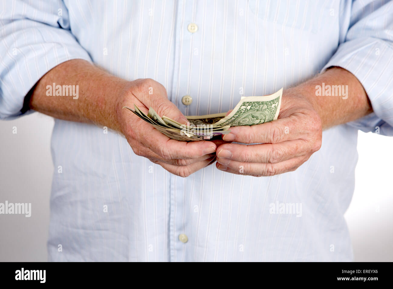 Mature man counts his cash money which are US dollar bills. Stock Photo