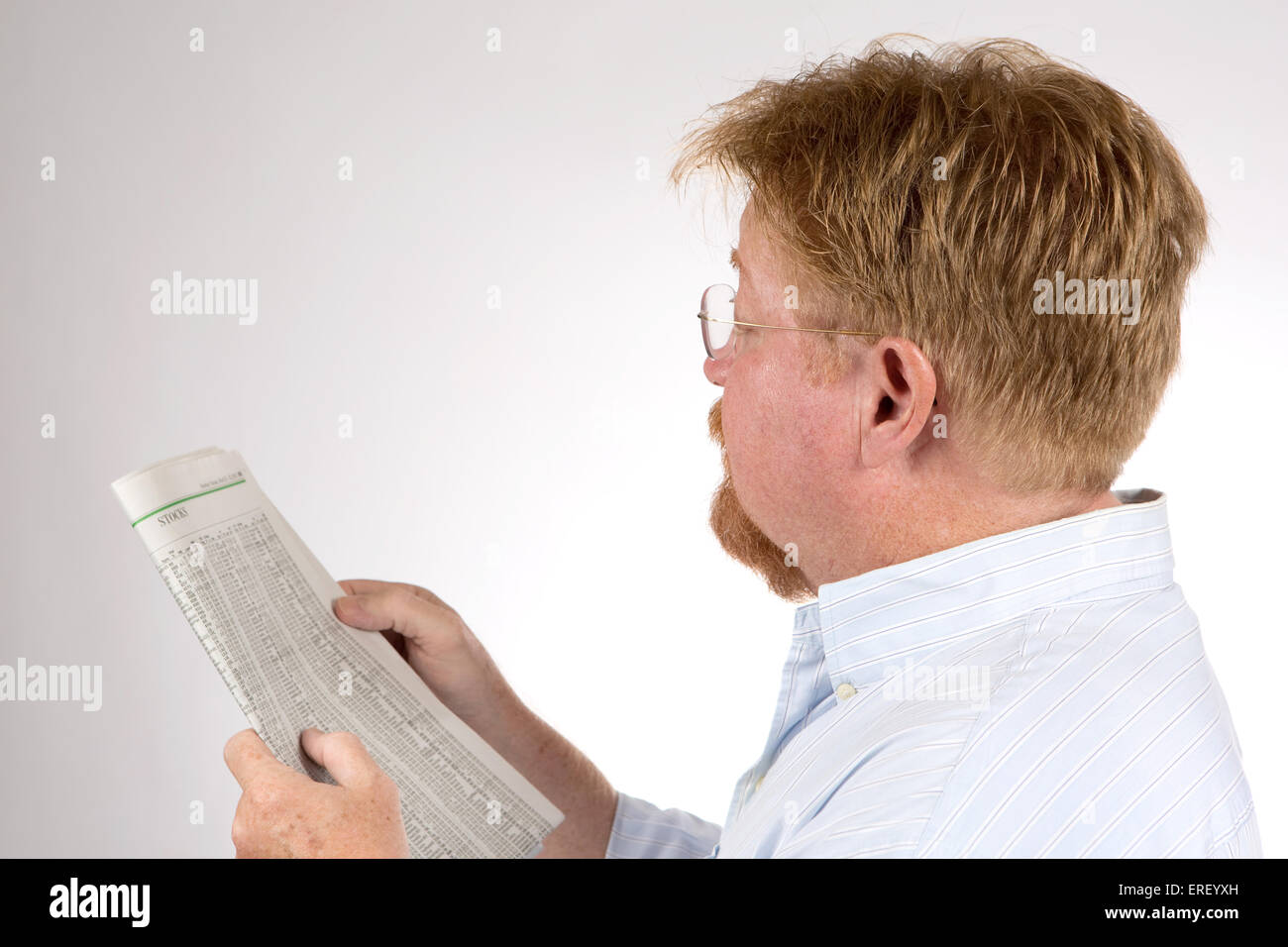 Mature male reads the stock market report in the newspaper to glean financial information and improve his investments. Stock Photo