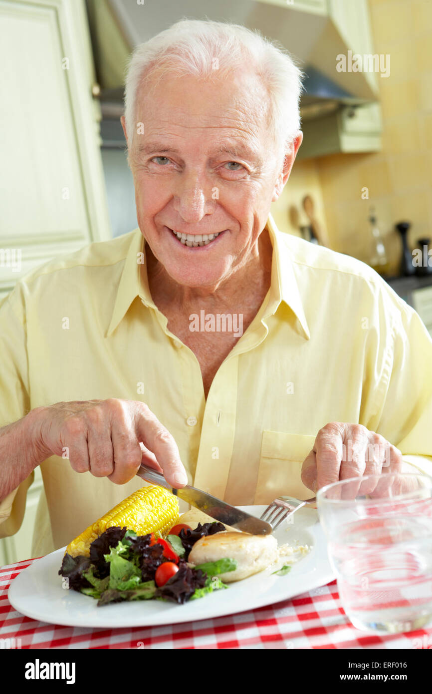 Senior Man Eating Meal In Kitchen Stock Photo