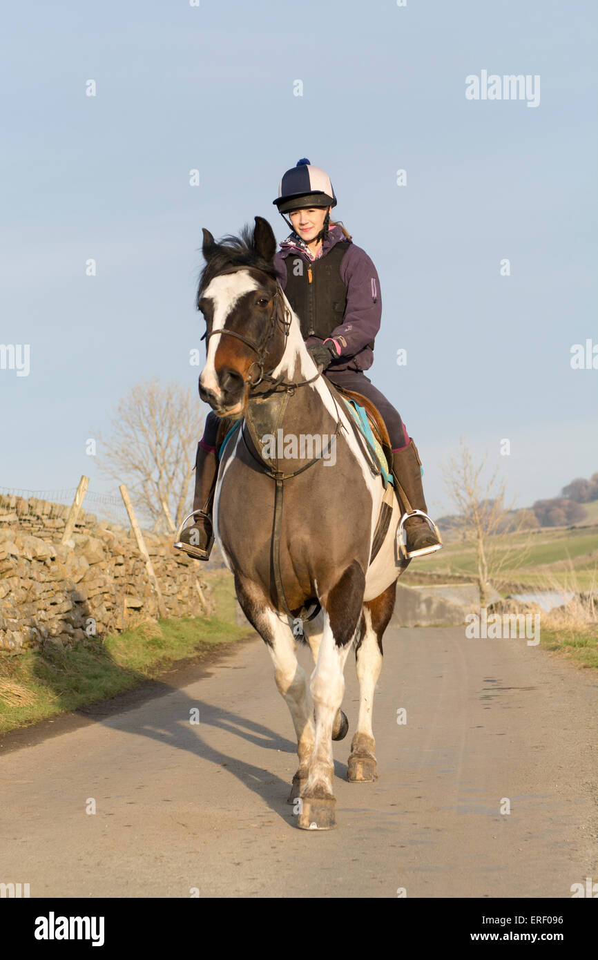 Girl taking a pony for a hack ride along country lanes around Hawes, North Yorkshire, UK. Stock Photo