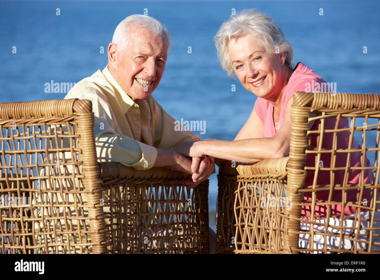 Senior Couple Sitting In Chairs Relaxing On Beach Stock Photo
