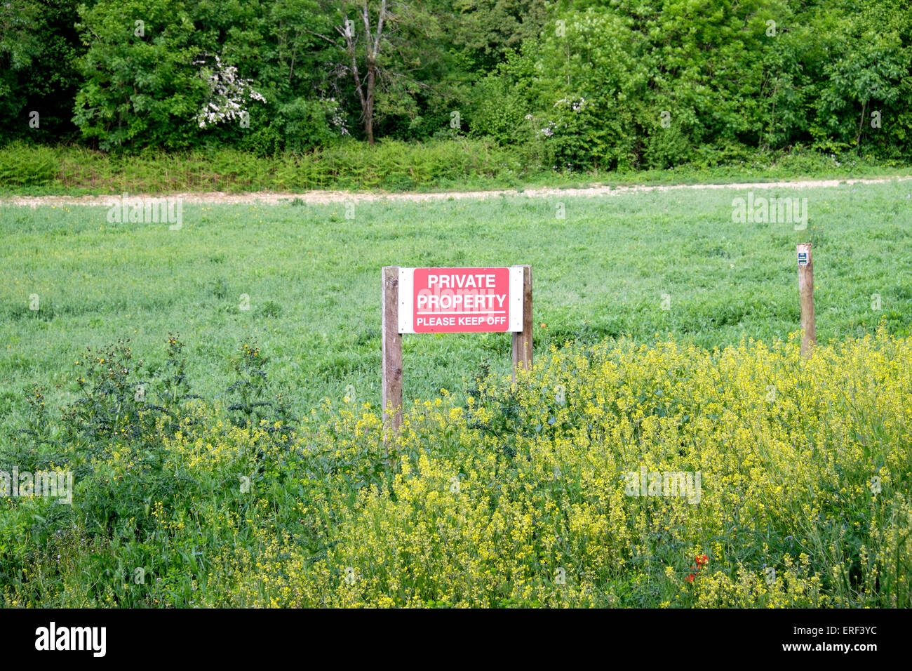 Red private property notice with white text standing on agricultural land in UK Stock Photo