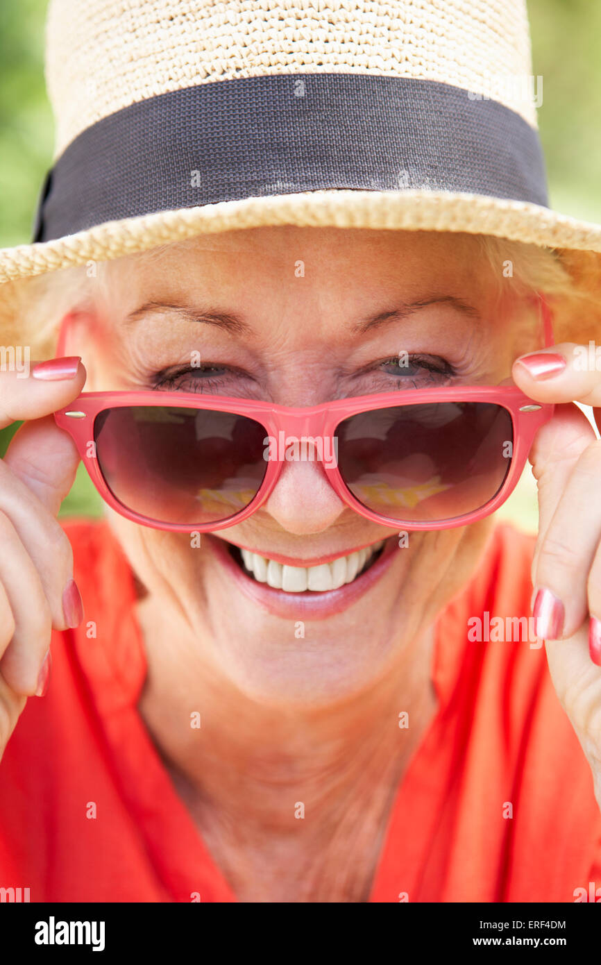 Head And Shoulders Portrait Of Smiling Senior Woman Wearing Sunglasses