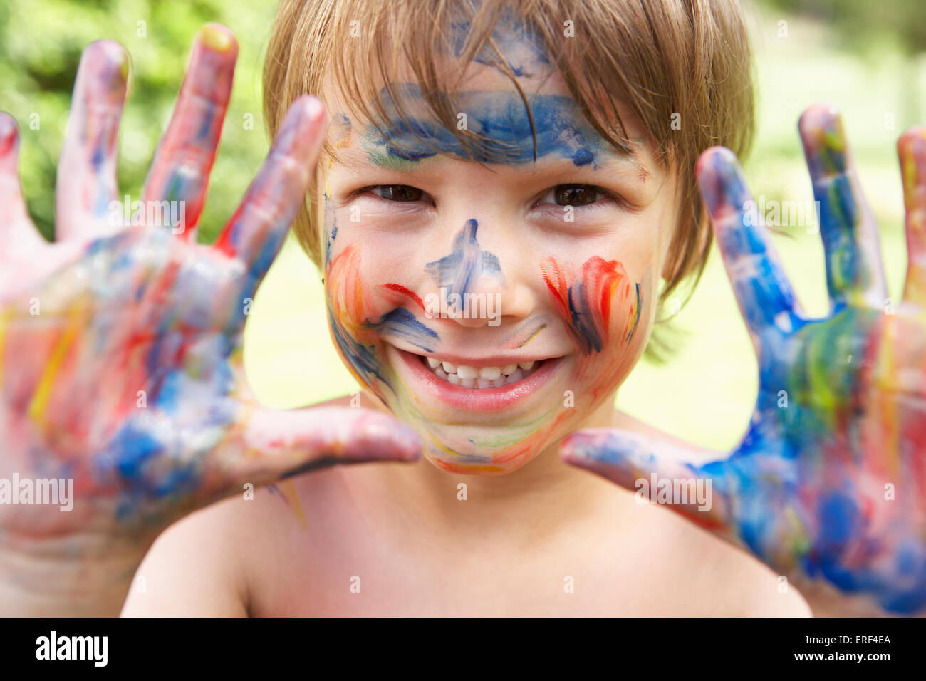 Head And Shoulders Portrait Of Boy With Painted Face and Hands Stock Photo