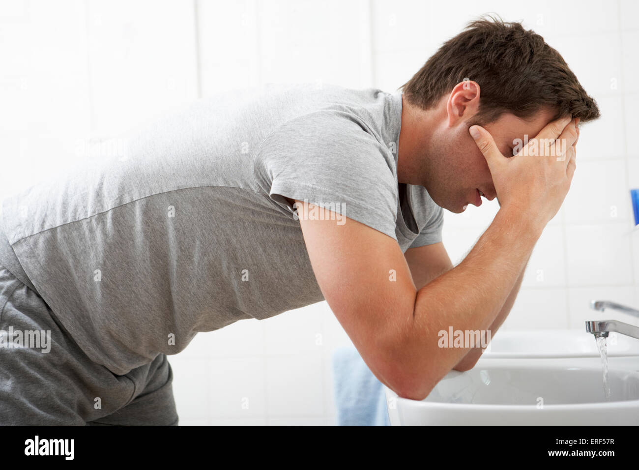 Tired Man In Standing At Bathroom Sink Stock Photo
