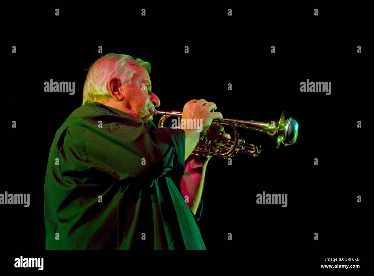 Older trumpet player playing the instrument with a mute. The trumpeter