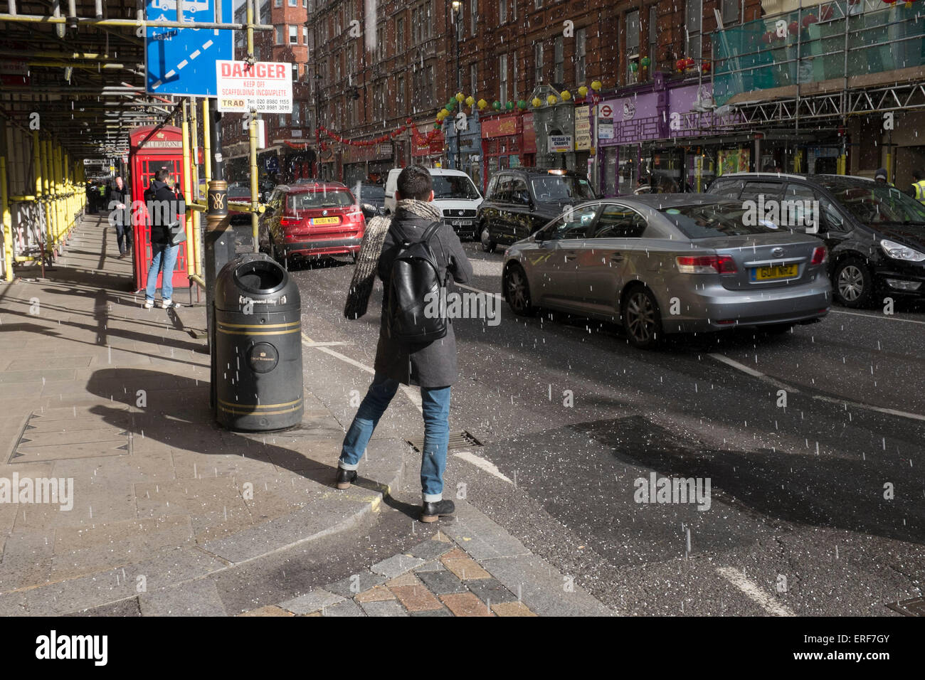 Sudden hail storm on a sunny day on Shaftesbury Avenue takes people by surprise in London, UK. Changeable weather of springtime. Stock Photo