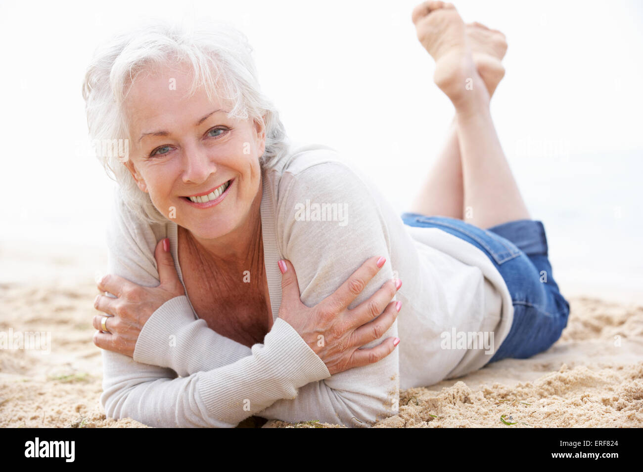 Senior Woman Relaxing On Beach Stock Photo - Alamy