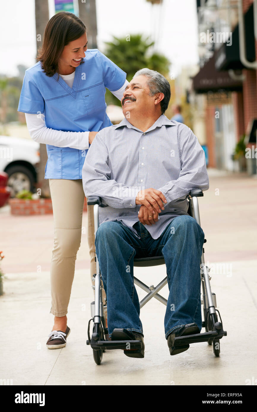 Carer Pushing Disabled Senior Man In Wheelchair Stock Photo