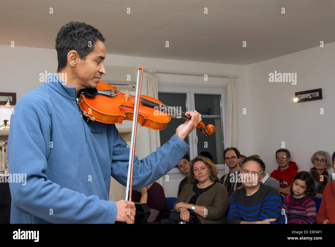 Male viola player performing to a small audience in an informal private