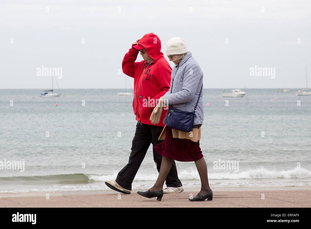 United Kingdom, Swanage : A couple wrap up as they walk along the beach in the rain in Swanage, Dorset, on June 1, 2015. Stock Photo