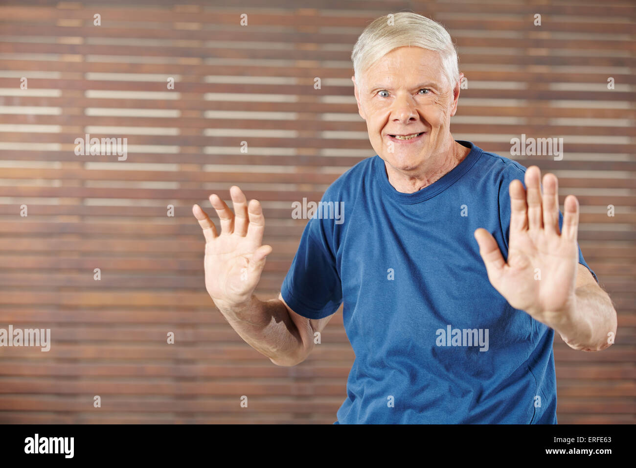 Old man doing gymnastics in fitness center and moving his hands Stock Photo