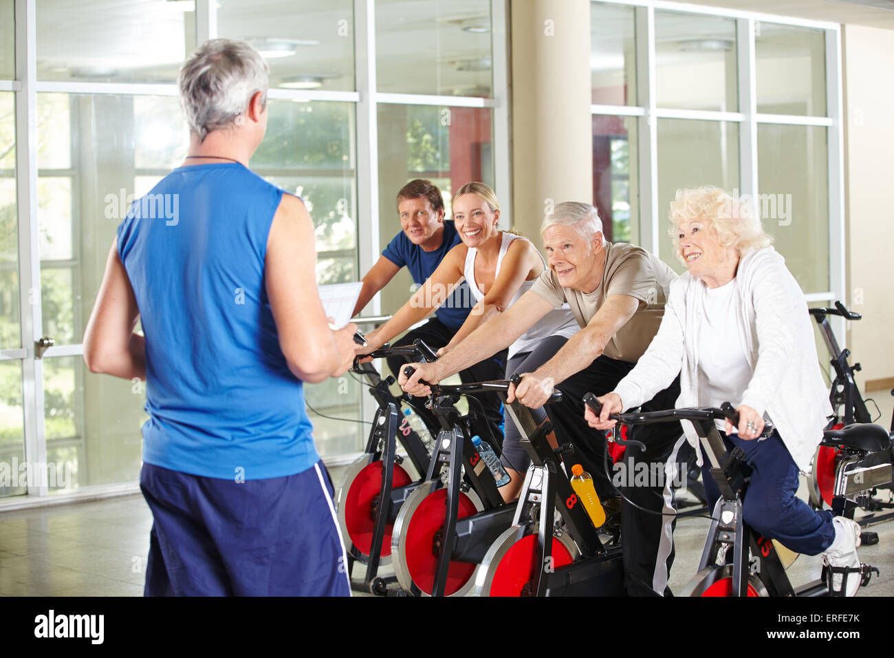 Senior people in rehab care center with instructor riding spinning bikes in  gym Stock Photo - Alamy