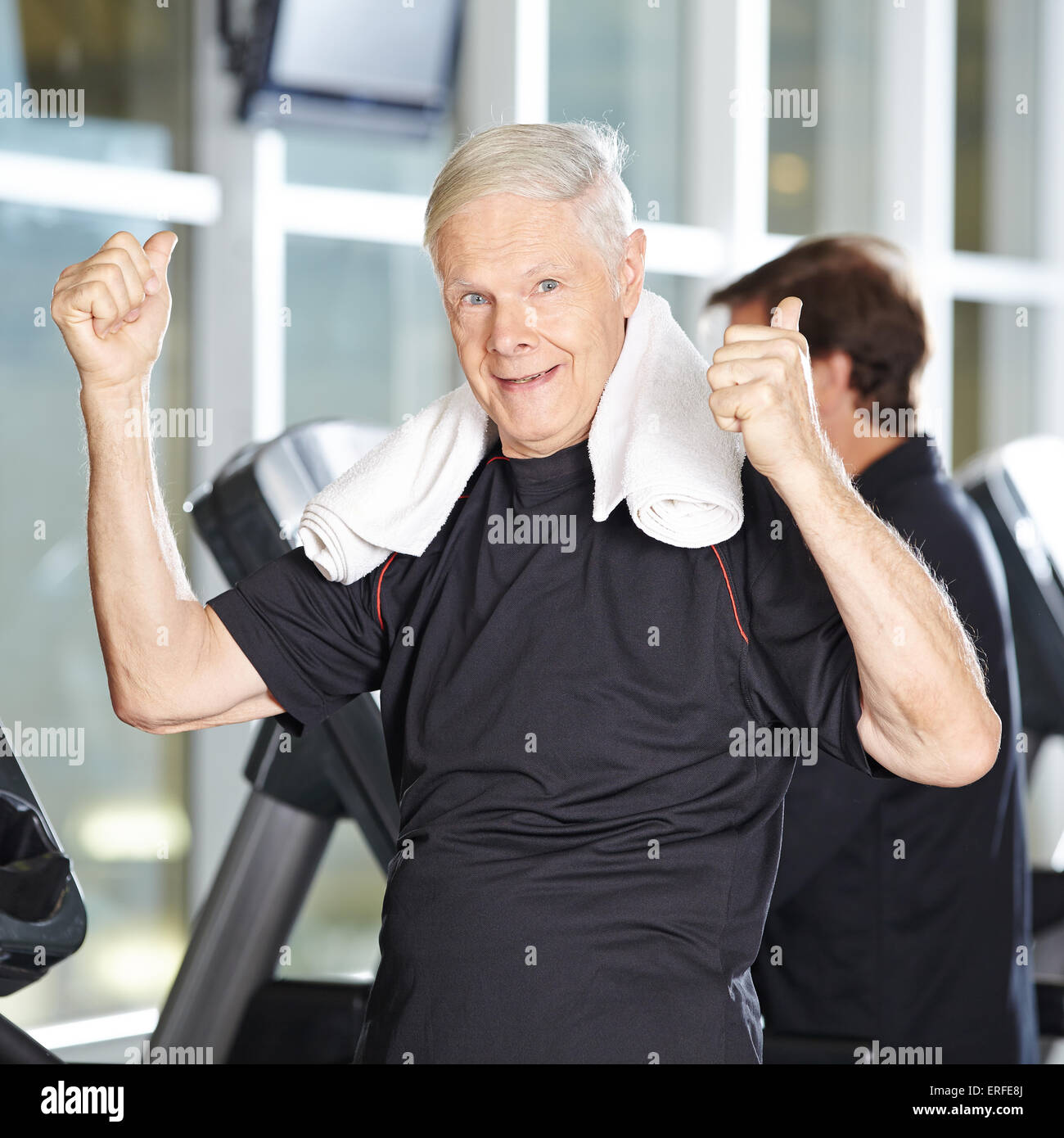 Old man on treadmill in fitness center holding his thumbs up Stock Photo
