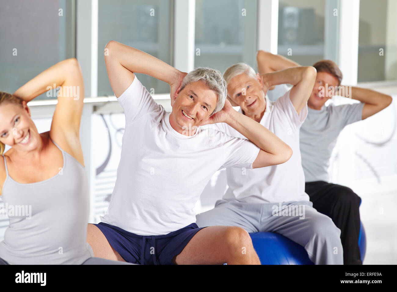 Happy senior group doing back training on gym balls in fitness center Stock Photo