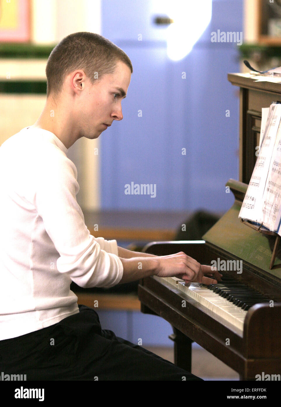 Young pianist Dan Perkins playing on upright piano with score. Stock Photo