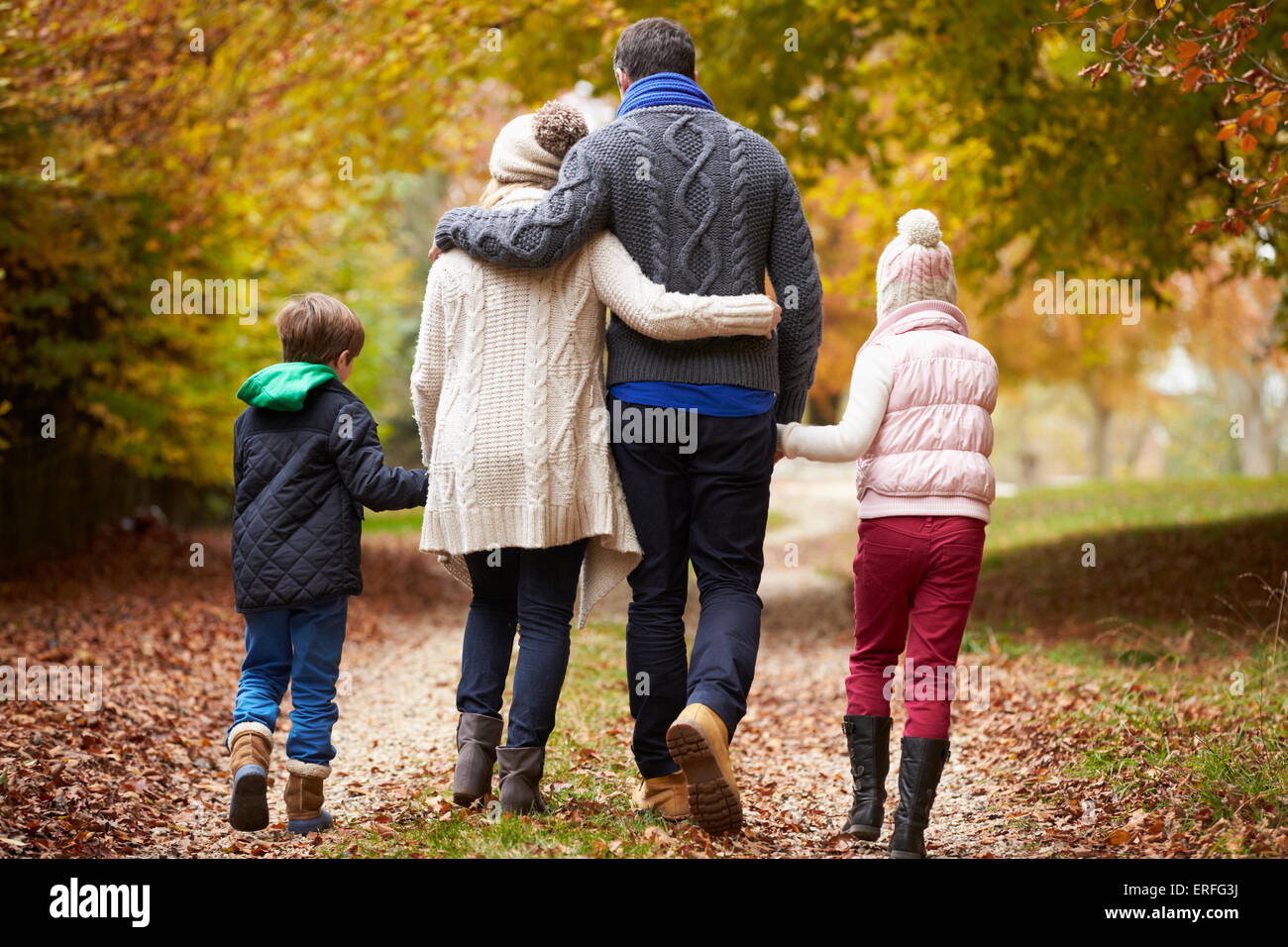 Rear View Of Family Walking Along Autumn Path Stock Photo