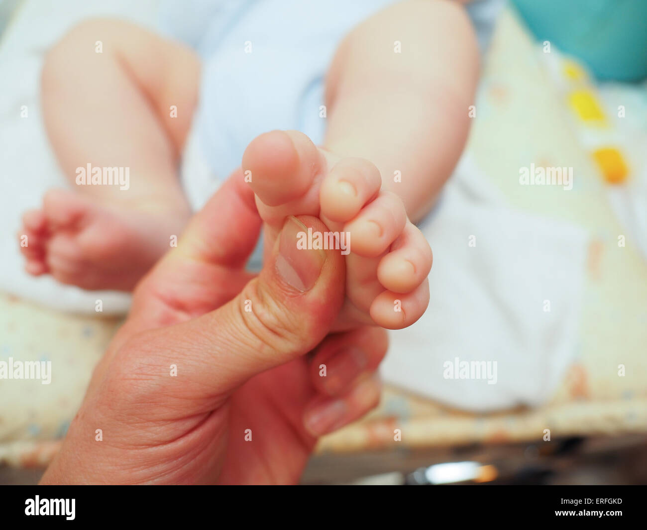 Baby receiving foot massage after diaper change with a thumb Stock Photo