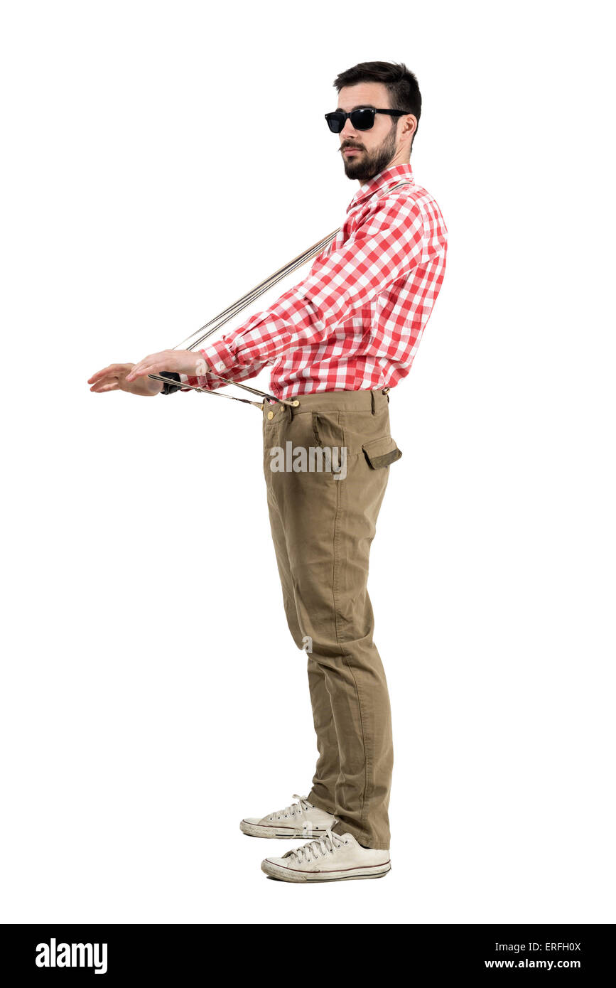 Eccentric hipster stretching suspenders looking at distance. Full body length portrait isolated over white background. Stock Photo