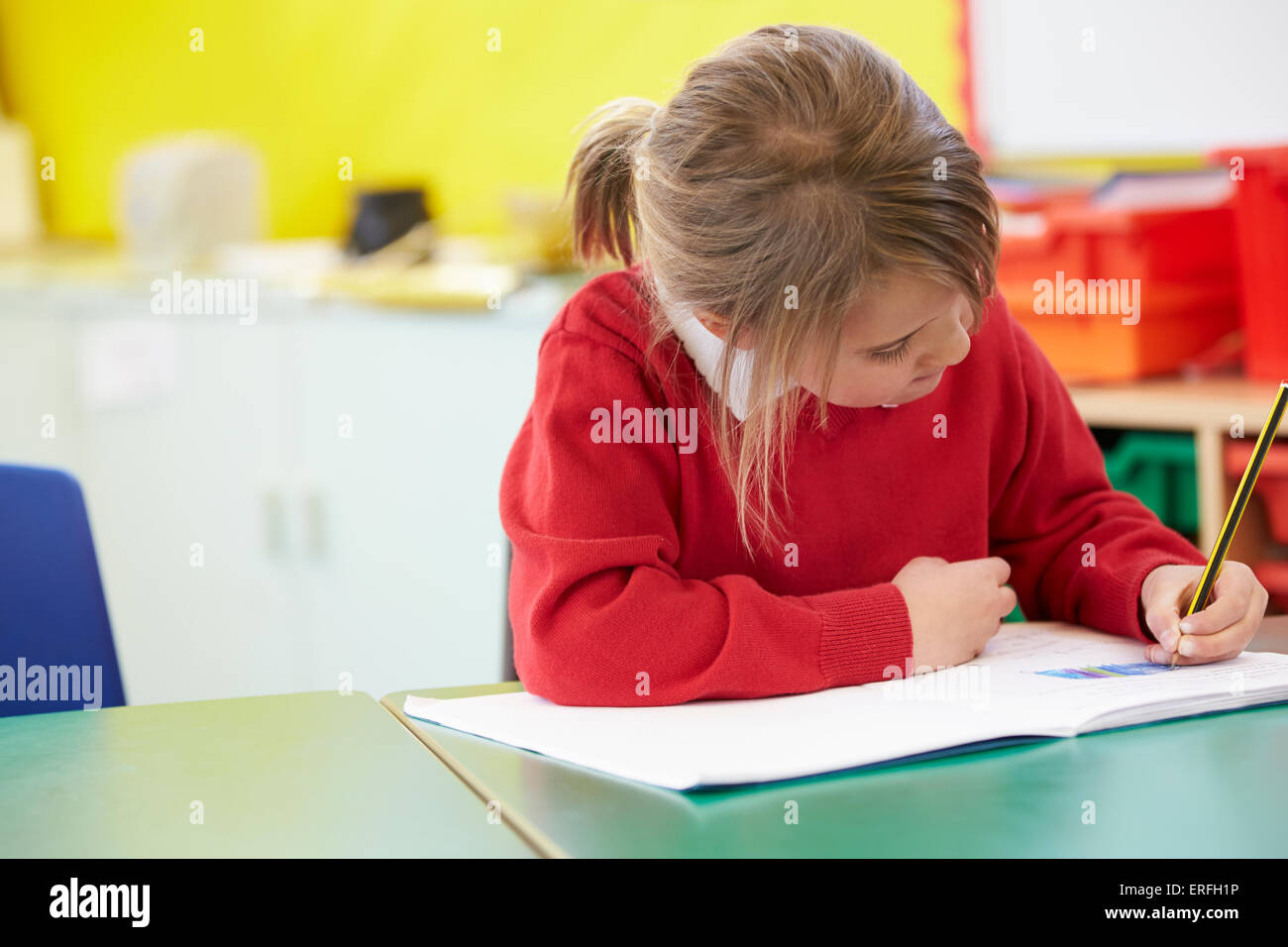 Female Pupil Practising Writing At Table Stock Photo