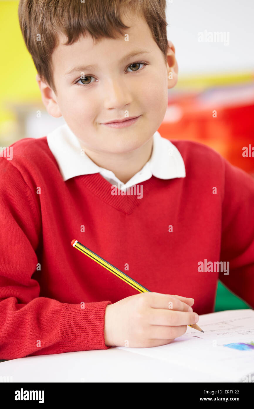 Male Pupil Practising Writing At Table Stock Photo