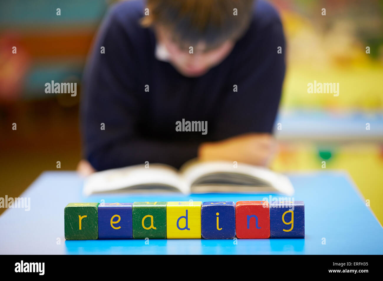 Word 'Reading' Spelt In Wooden Blocks With Pupil Behind Stock Photo