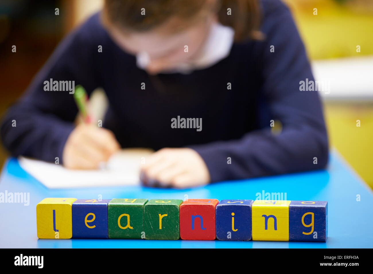 Word 'Learning' Spelt In Wooden Blocks With Pupil Behind Stock Photo
