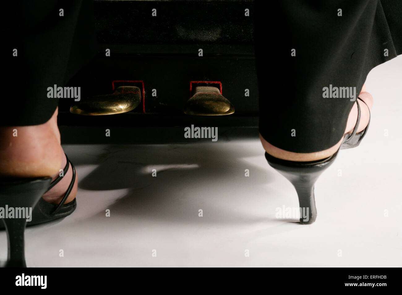 Piano - close-up of the pedals on a grand piano being played by a female pianist in high heels.   Amanda Buckley Stock Photo
