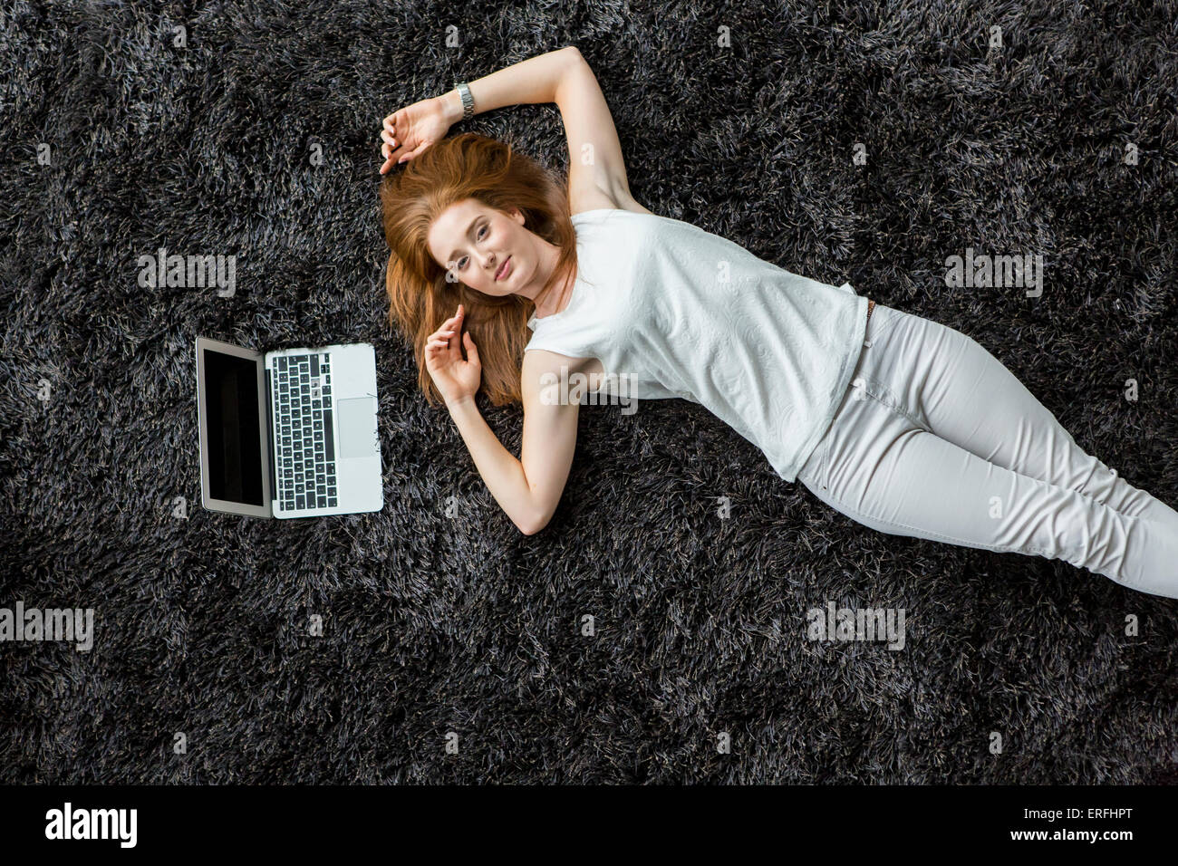 Young woman laying on the carpet Stock Photo - Alamy