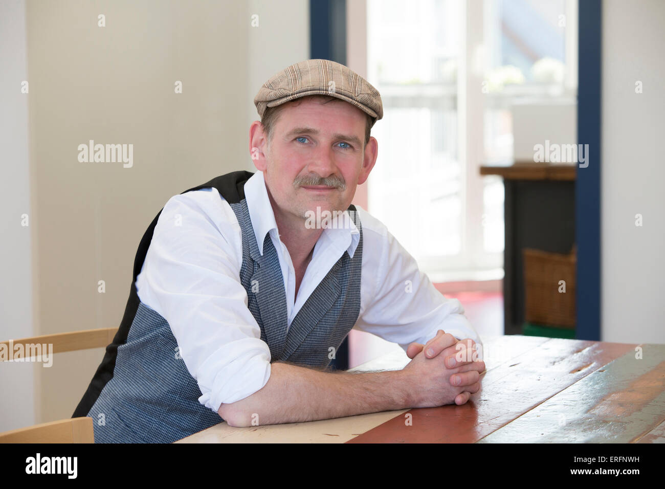 man in his 50's sitting at table and smiles at camera Stock Photo