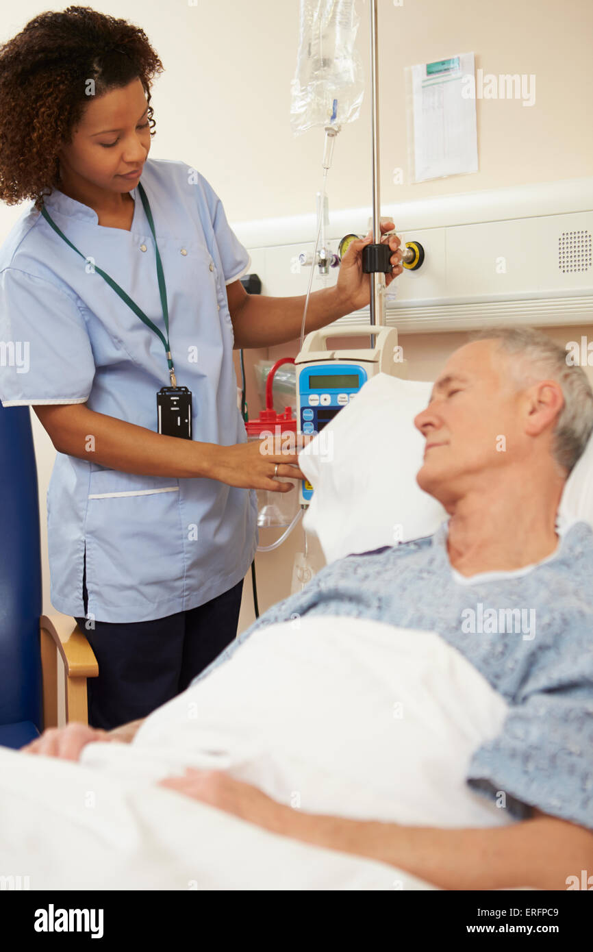 Nurse Adjusting Male Patient's IV Drip In Hospital Stock Photo