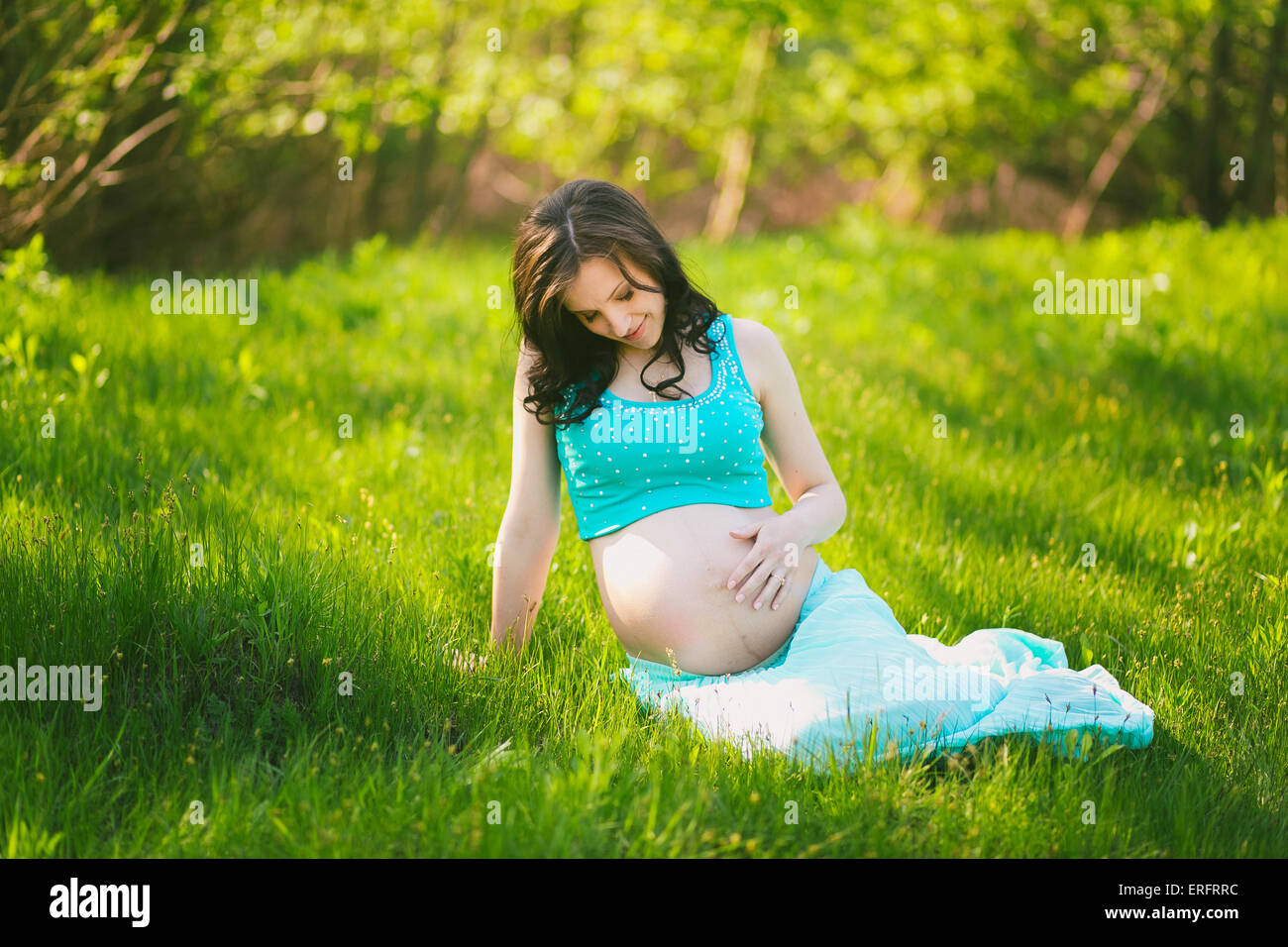 Young happy woman in expectation of baby. Female hands holding pregnant belly. Beautiful mother enjoying nature. Pregnant woman Stock Photo