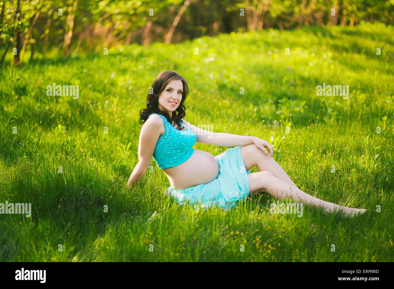 Young happy woman in expectation of baby. Female hands holding pregnant belly. Beautiful mother enjoying nature. Pregnant woman Stock Photo