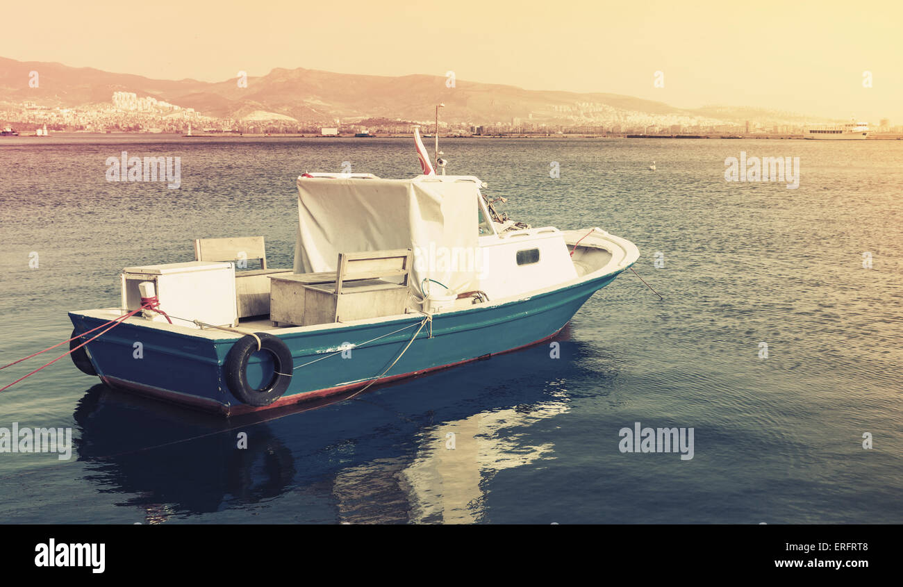 Old wooden pleasure boat anchored in Izmir bay, Turkey. Vintage stylized photo with yellow tonal correction photo filter, old st Stock Photo