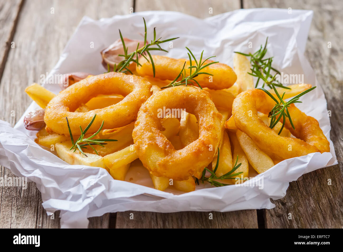 french fries with calamari and rosemary on white paper Stock Photo