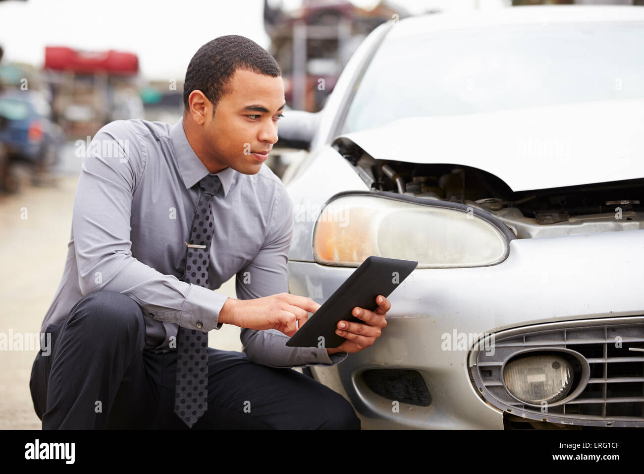 Loss Adjuster Using Digital Tablet In Car Wreck Inspection Stock Photo