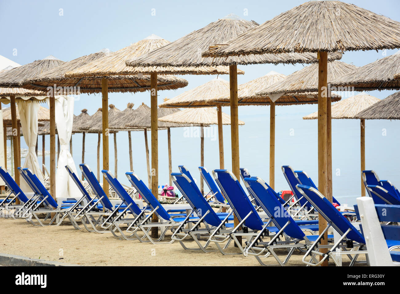Reed umbrellas and deck chairs at the beach Stock Photo
