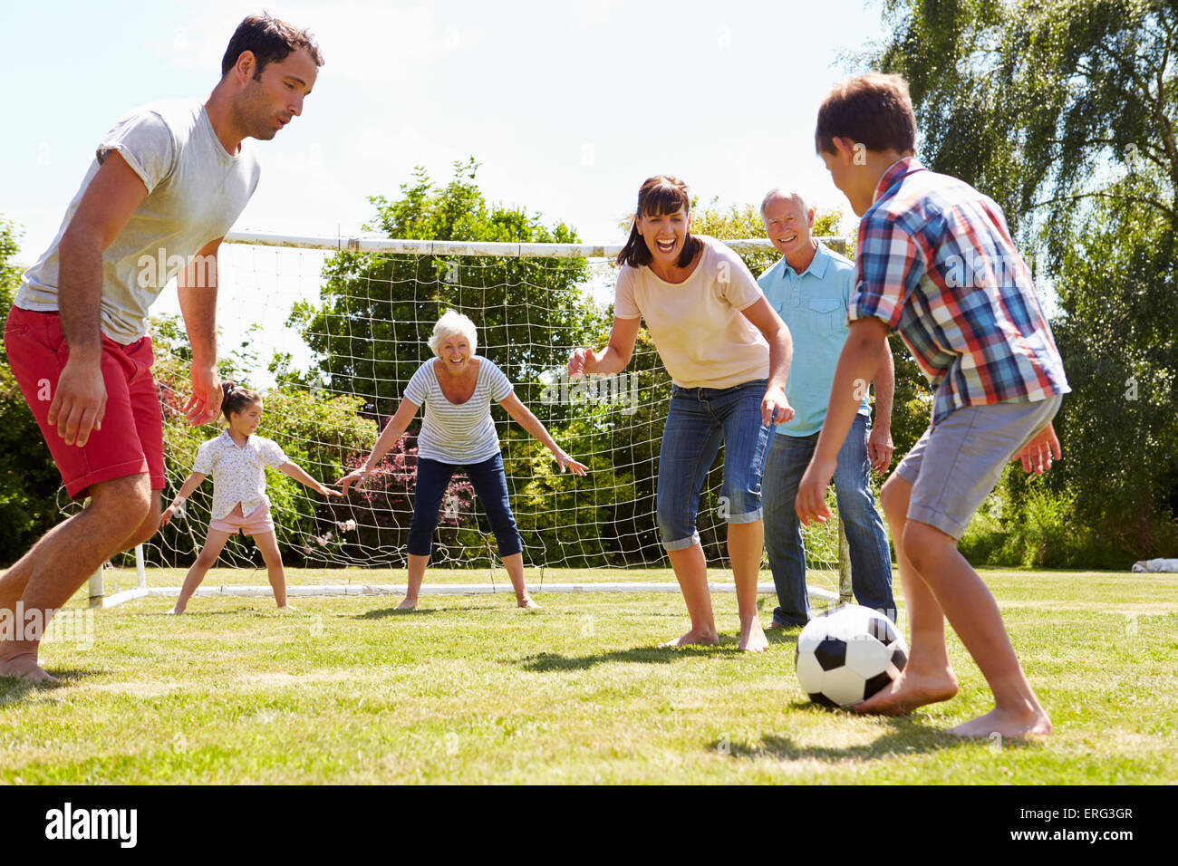 Multi Generation Playing Football In Garden Together Stock Photo - Alamy