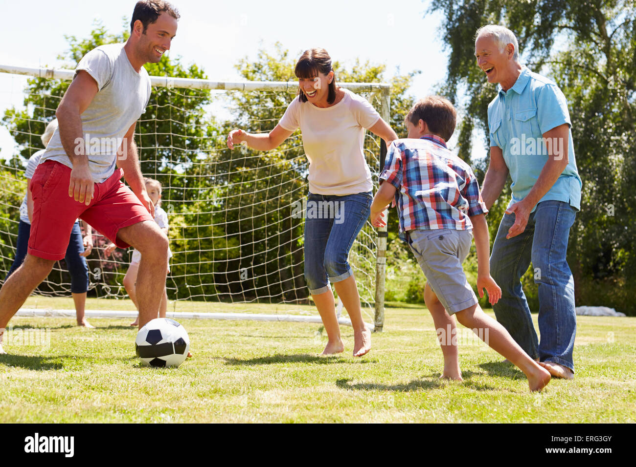 Multi Generation Playing Football In Garden Together Stock Photo - Alamy