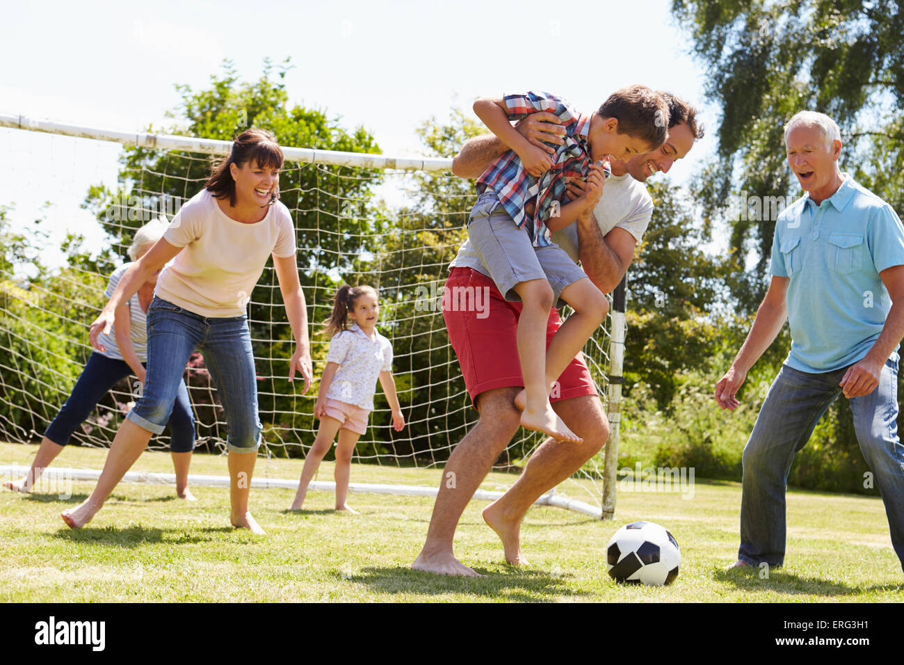 Multi Generation Playing Football In Garden Together Stock Photo - Alamy