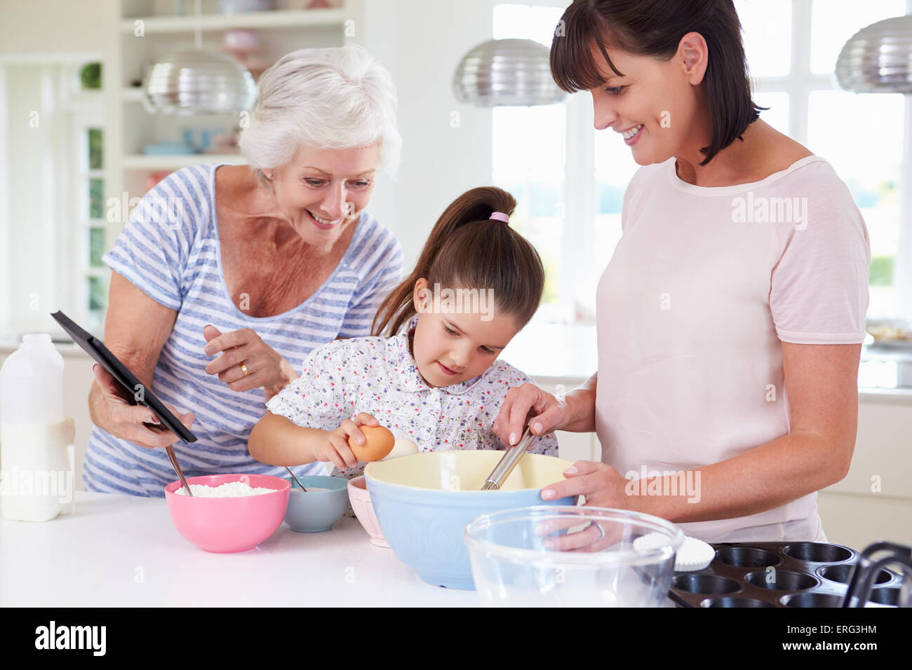 Grandmother, Granddaughter And Mother Baking Cake In Kitchen Stock Photo