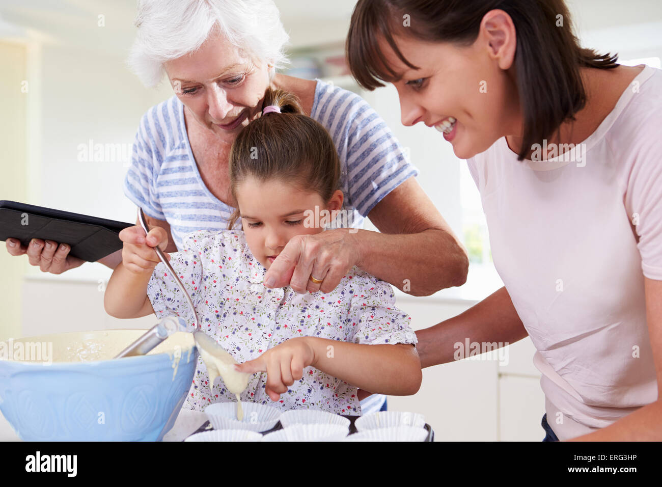 Grandmother, Granddaughter And Mother Baking Cake In Kitchen Stock Photo